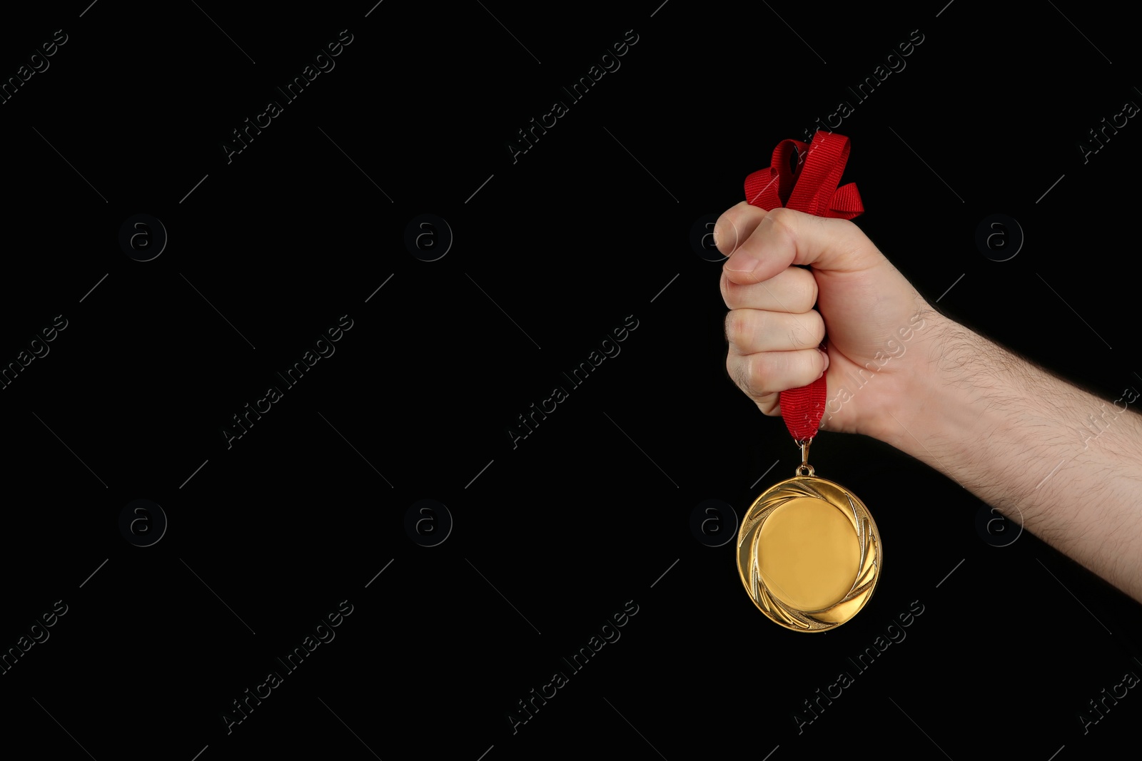 Photo of Man holding golden medal on black background, closeup. Space for design