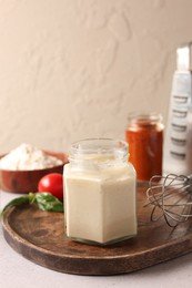 Photo of Pizza dough starter in glass jar and products on gray table