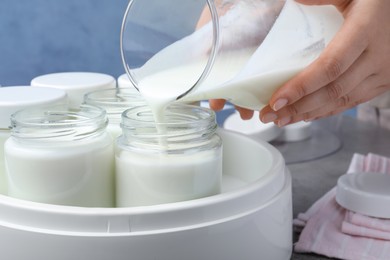 Photo of Woman pouring milk into glass jar, closeup. Making yogurt