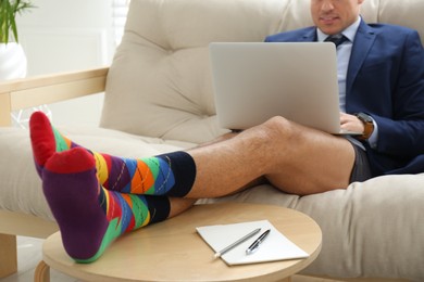 Photo of Businessman in jacket and underwear working on laptop at home, closeup