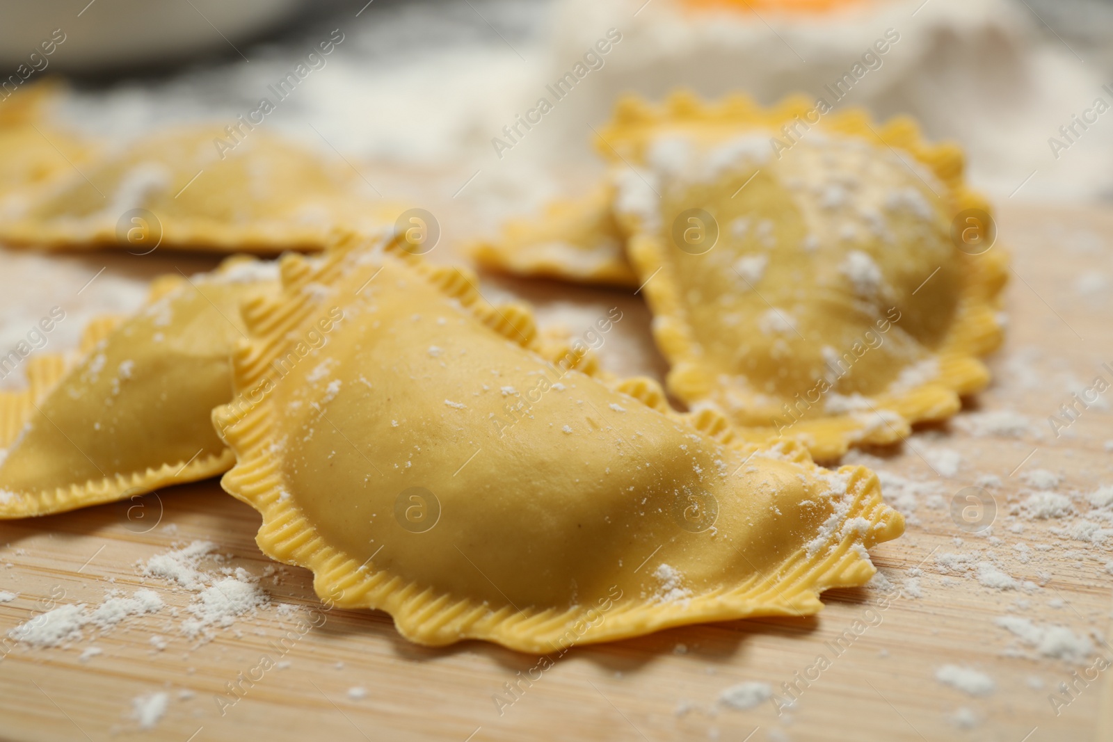 Photo of Raw ravioli on wooden board, closeup view. Italian pasta