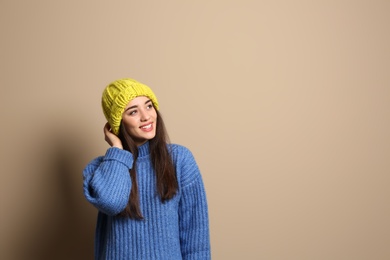 Young woman wearing warm clothes on color background, space for text. Winter season