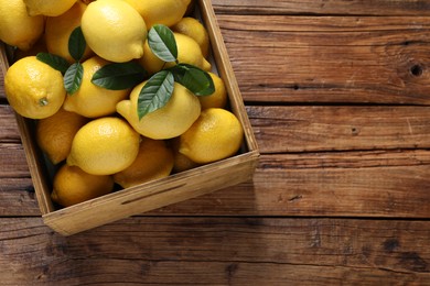 Fresh lemons in crate on wooden table, top view. Space for text