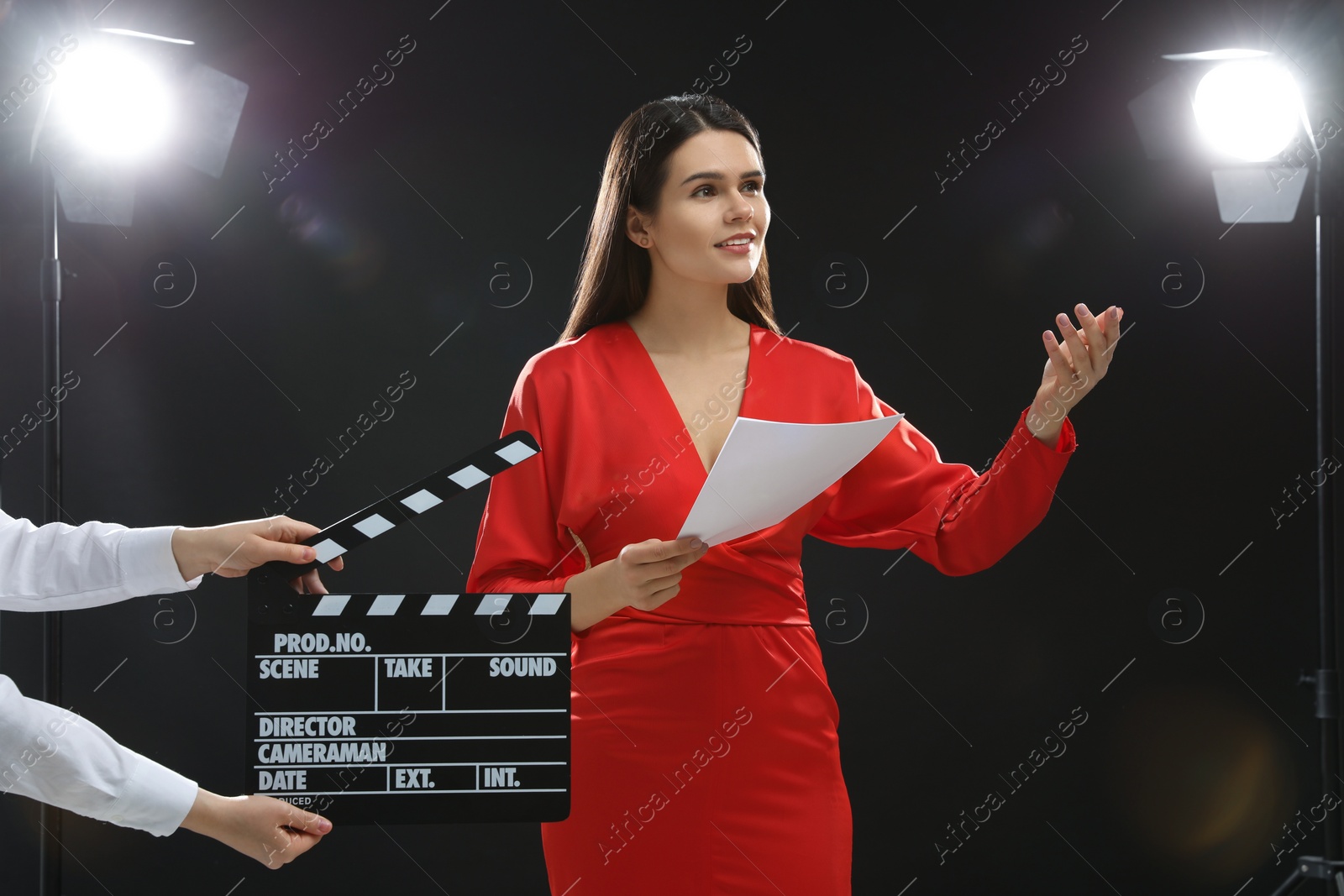Photo of Emotional actress performing role while second assistant camera holding clapperboard on stage. Film industry