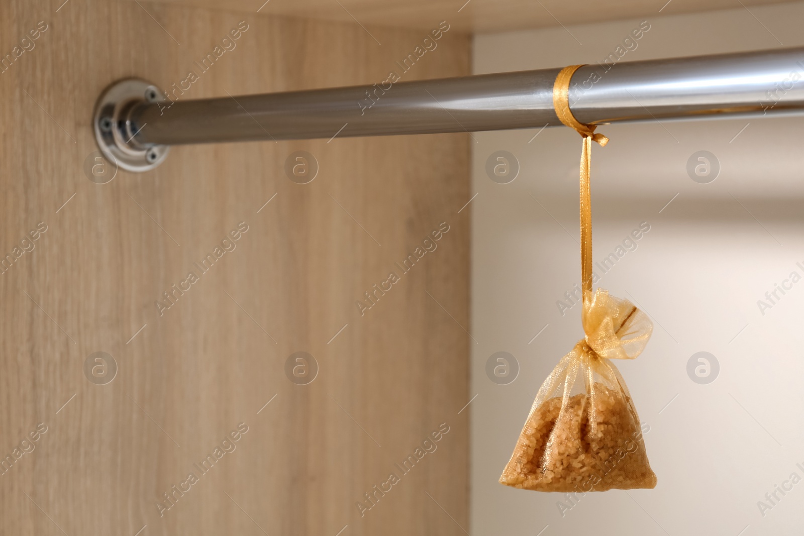 Photo of Scented sachet hanging on metal bar in wardrobe