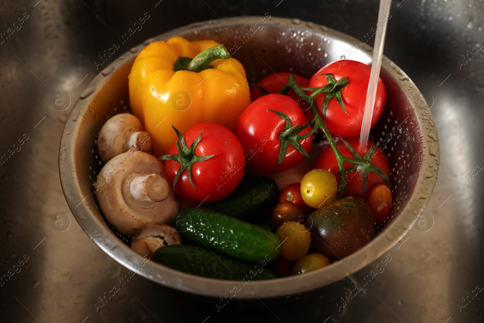 Photo of Washing different vegetables with tap water in metal colander inside sink