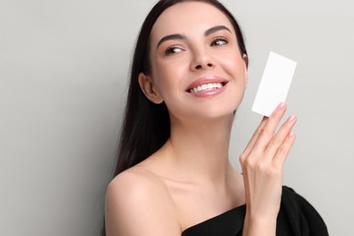 Photo of Happy woman holding blank business card on light grey background