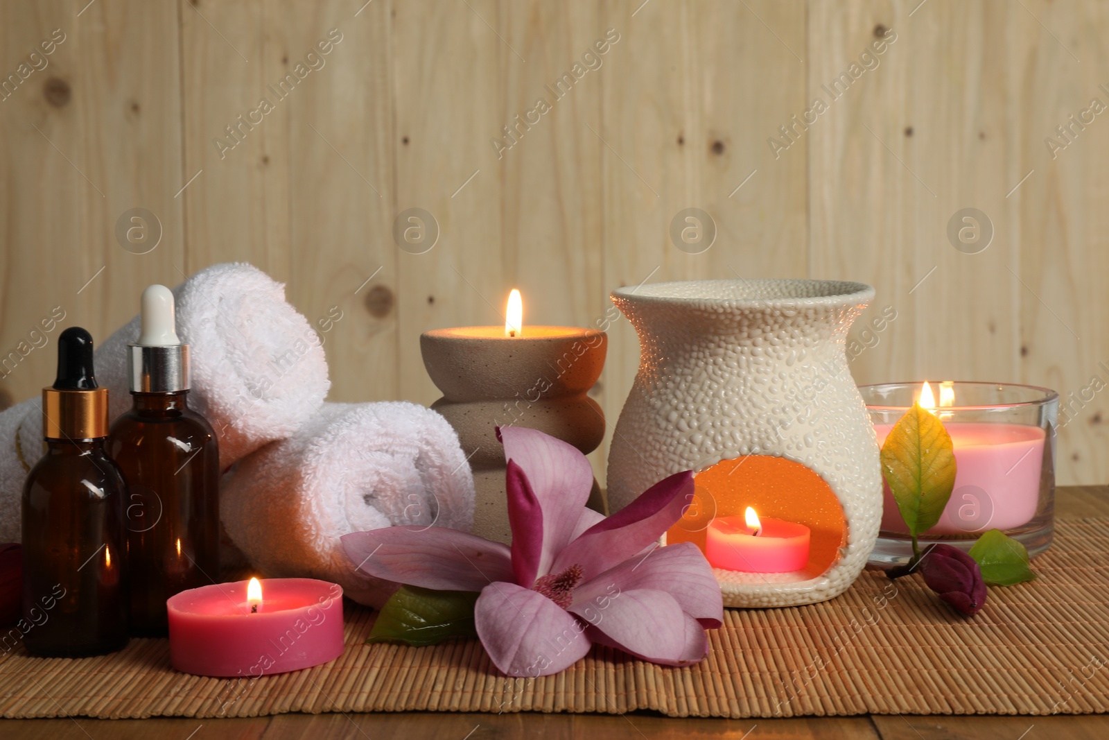 Photo of Aromatherapy. Scented candles, bottles, flower and towels on table