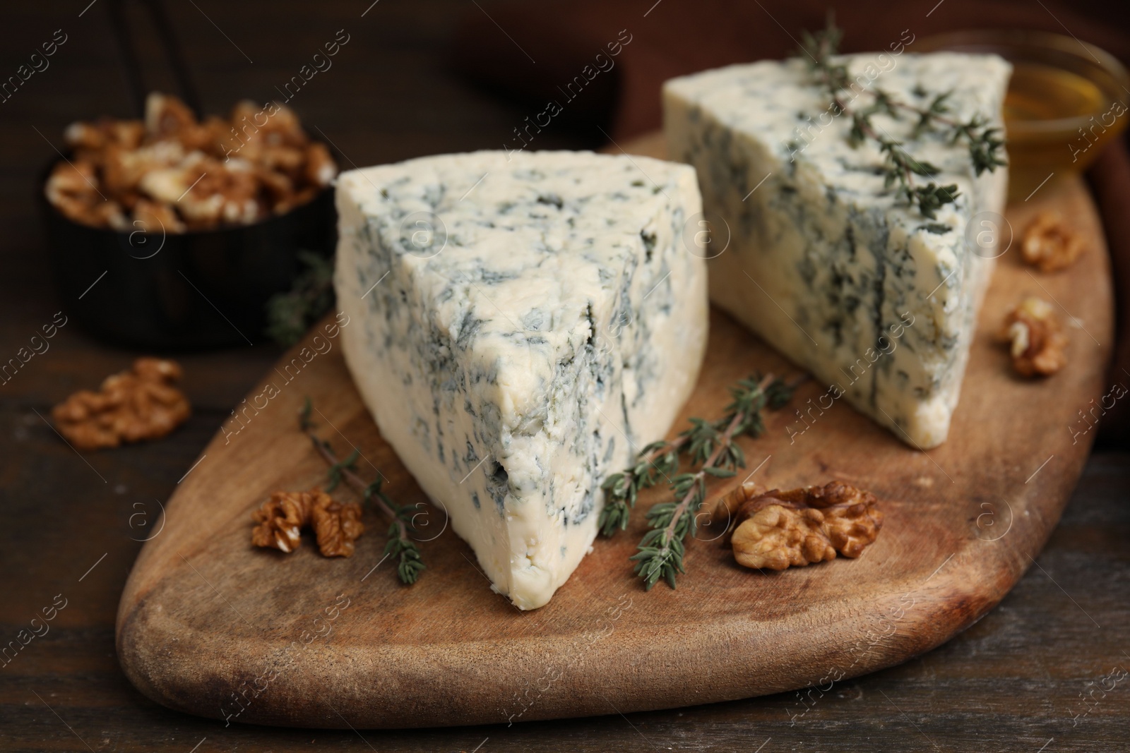 Photo of Tasty blue cheese with thyme and walnuts on wooden table, closeup