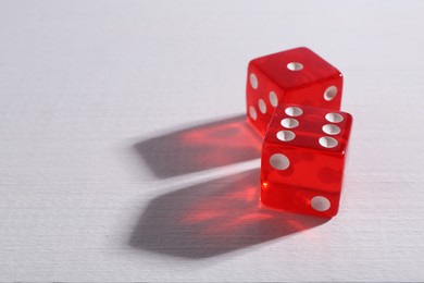 Photo of Two red game dices on white wooden table, closeup. Space for text