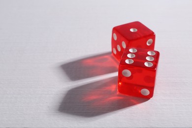 Two red game dices on white wooden table, closeup. Space for text