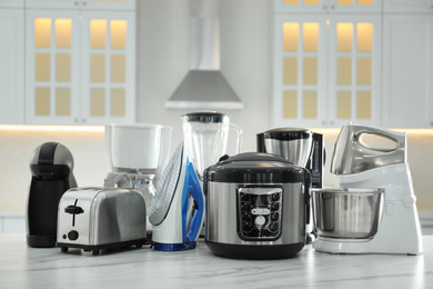 Photo of Set of modern home appliances on white marble table in kitchen