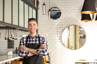 Portrait of young waiter in uniform at cafe