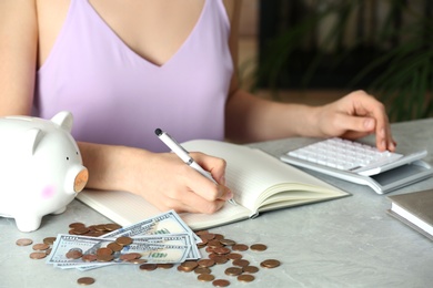 Photo of Woman counting coins at grey marble table, closeup. Money savings