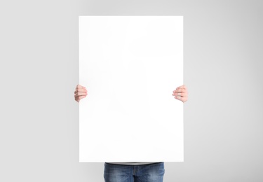 Photo of Man holding blank poster on light grey background