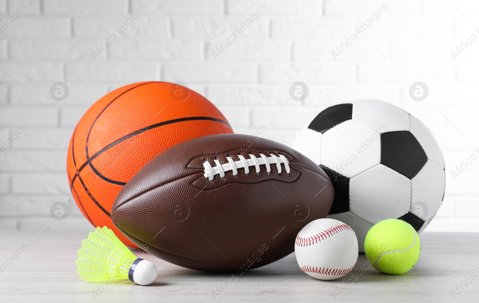 Photo of Set of different sport balls and shuttlecock on light wooden table