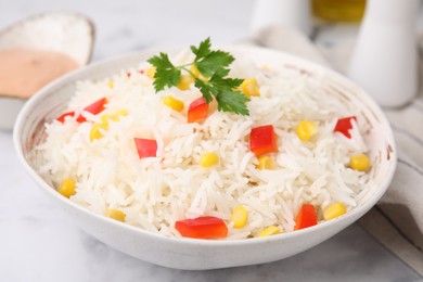 Photo of Bowl of delicious rice with vegetables and parsley on light table, closeup