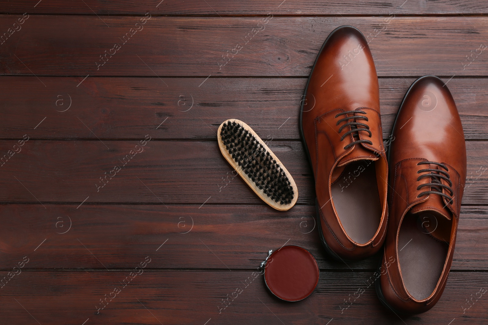 Photo of Flat lay composition with shoe care accessories and footwear on brown wooden background. Space for text