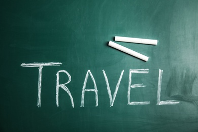 Photo of Word TRAVEL and chalk on blackboard, top view. Tourist agency