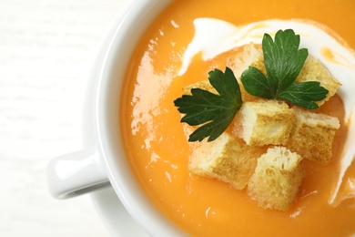 Photo of Delicious pumpkin soup in bowl on white table, closeup