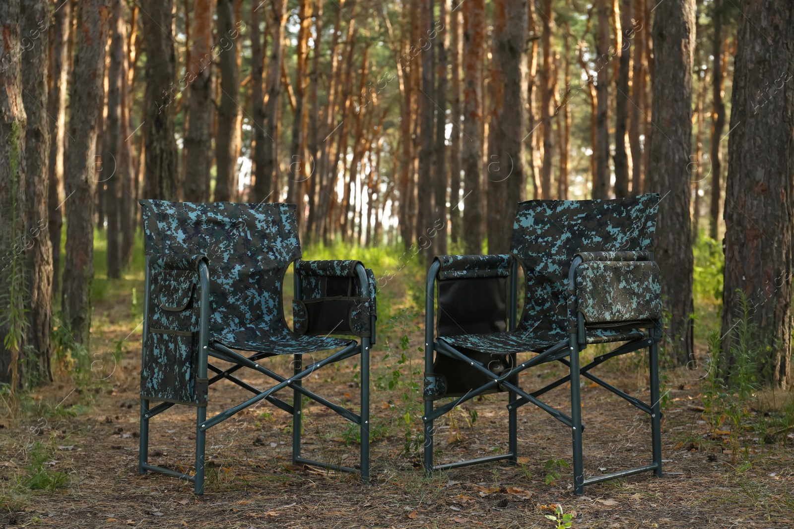 Photo of Camouflage chairs in forest on sunny day