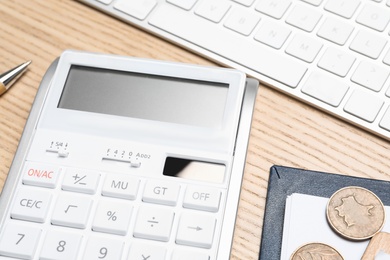 Photo of Calculator, money, keyboard and stationery on wooden table, closeup. Tax accounting