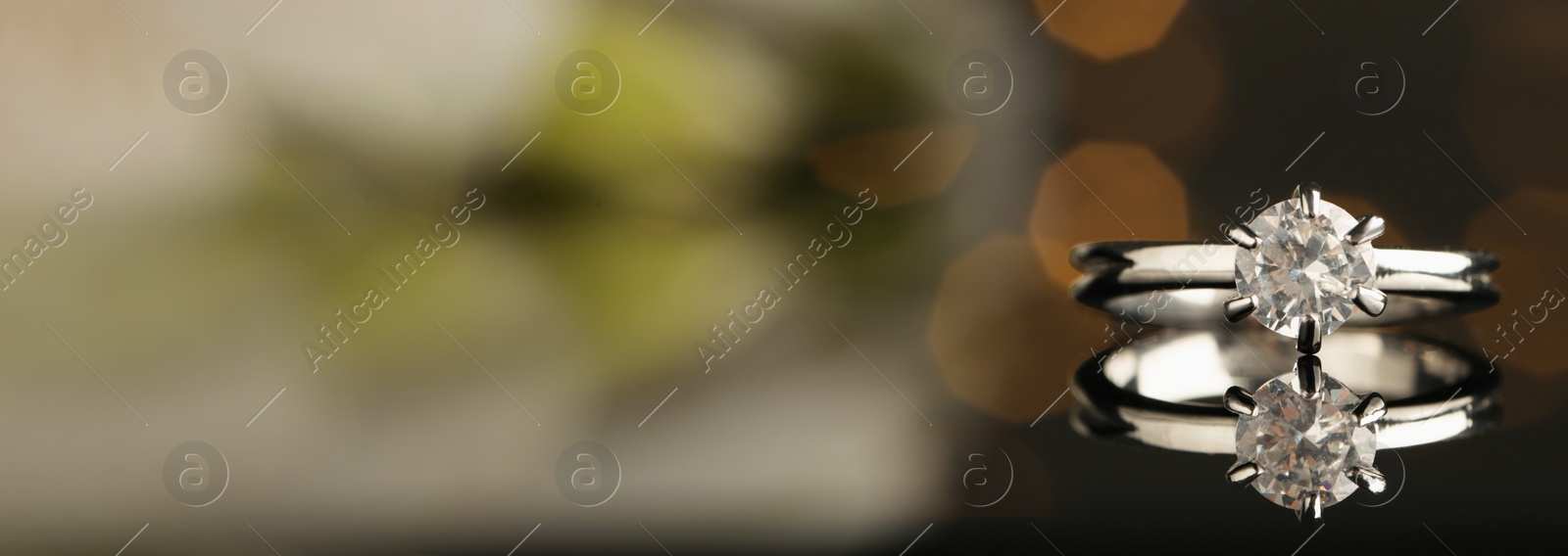 Image of Beautiful engagement ring against blurred festive lights, closeup view with space for text. Banner design