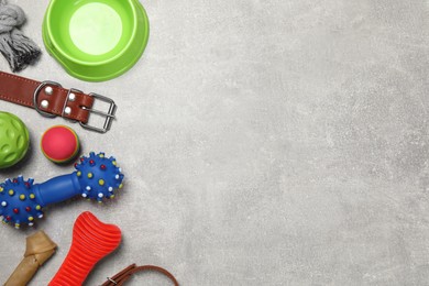 Photo of Flat lay composition with dog collar, toys and bowl on grey table. Space for text