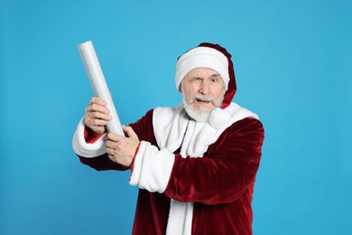 Photo of Man in Santa Claus costume with party popper winking on light blue background