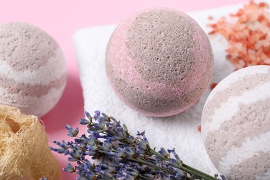 Photo of Bath bombs, towel, lavender and loofah sponge on pink background, closeup