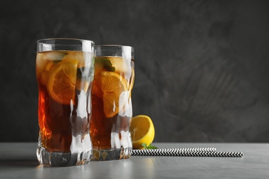 Photo of Glasses of refreshing iced tea on table against grey background. Space for text