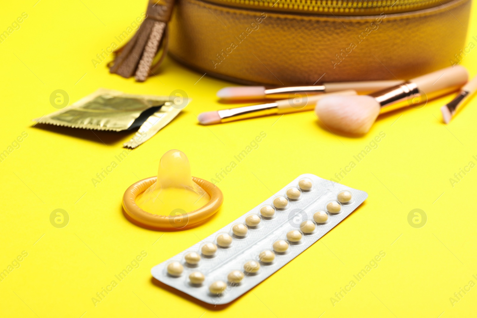 Photo of Condom and birth control pills on yellow background. Safe sex concept