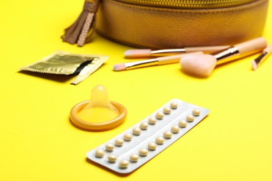 Condom and birth control pills on yellow background. Safe sex concept