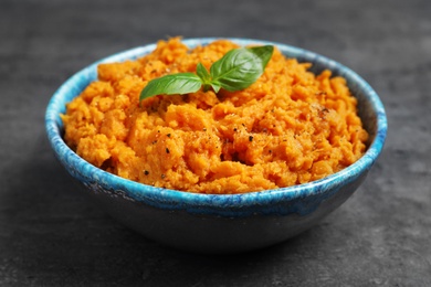 Photo of Bowl of tasty sweet potato puree on grey table