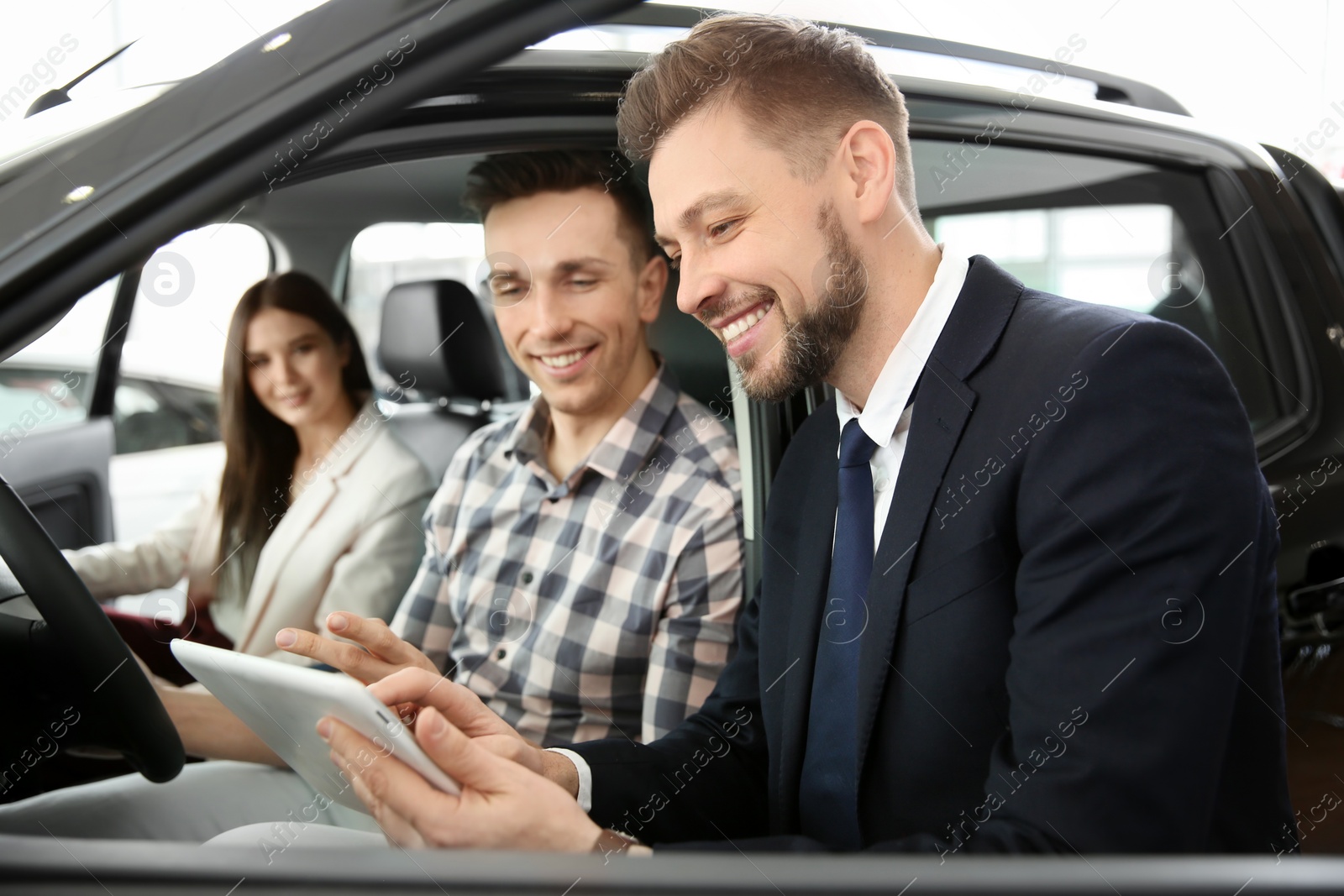 Photo of Young couple buying new car in salon