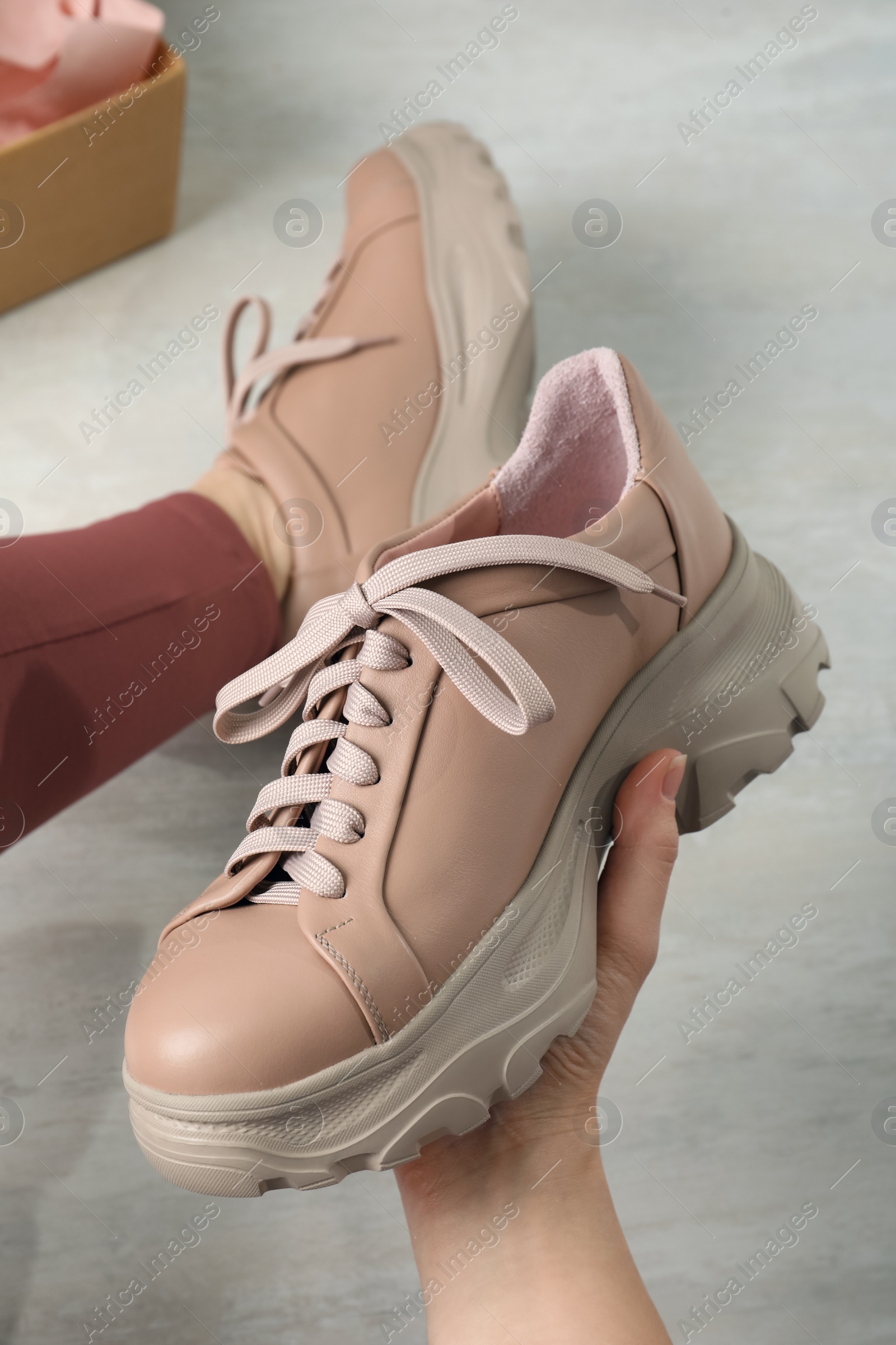 Photo of Young woman trying on shoes indoors, closeup