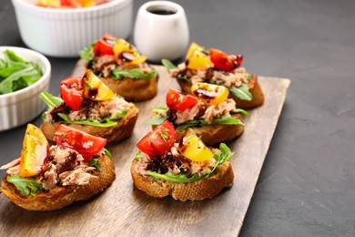 Delicious bruschettas with balsamic vinegar, tomatoes, arugula and tuna on grey textured table. Space for text