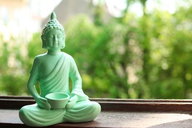 Photo of Decorative Buddha statue on wooden windowsill, space for text