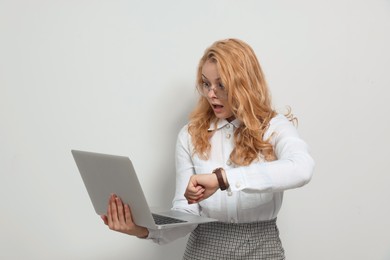 Emotional businesswoman with laptop in turmoil over being late on white background