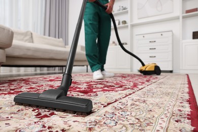 Photo of Dry cleaner's employee hoovering carpet with vacuum cleaner in room, closeup. Space for text