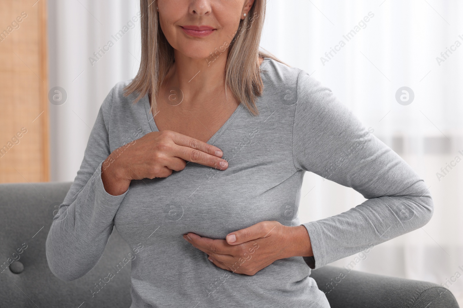 Photo of Woman doing breast self-examination at home, closeup