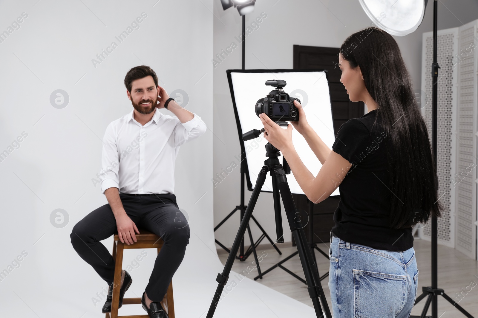 Photo of Professional photographer working with handsome model in modern photo studio