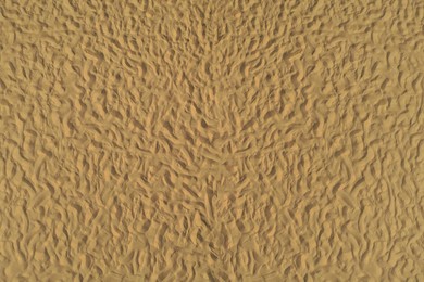 Golden beach sand on sunny day as background, top view