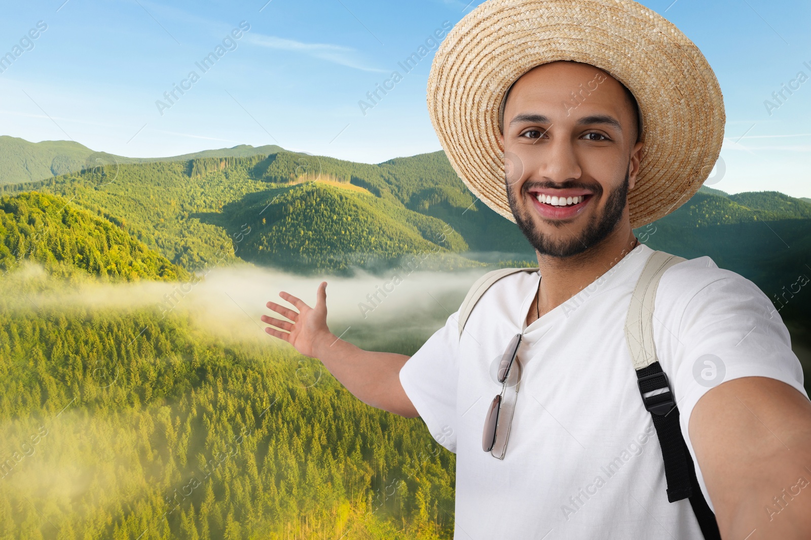 Image of Smiling young man in straw hat taking selfie in mountains