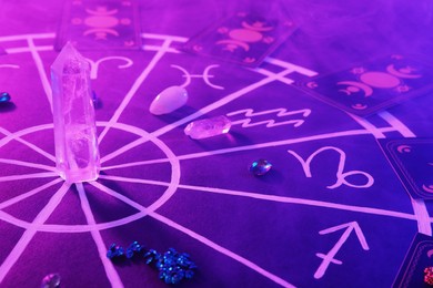 Natural stones for zodiac signs, tarot cards and drawn astrology chart on purple background. Color tone effect