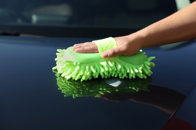 Photo of Man cleaning car hood outdoors, closeup view