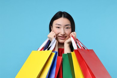 Photo of Happy woman with shopping bags on light blue background