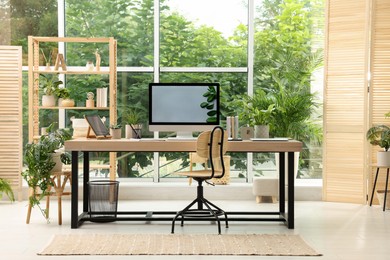 Photo of Comfortable workplace with computer in light room. Interior design