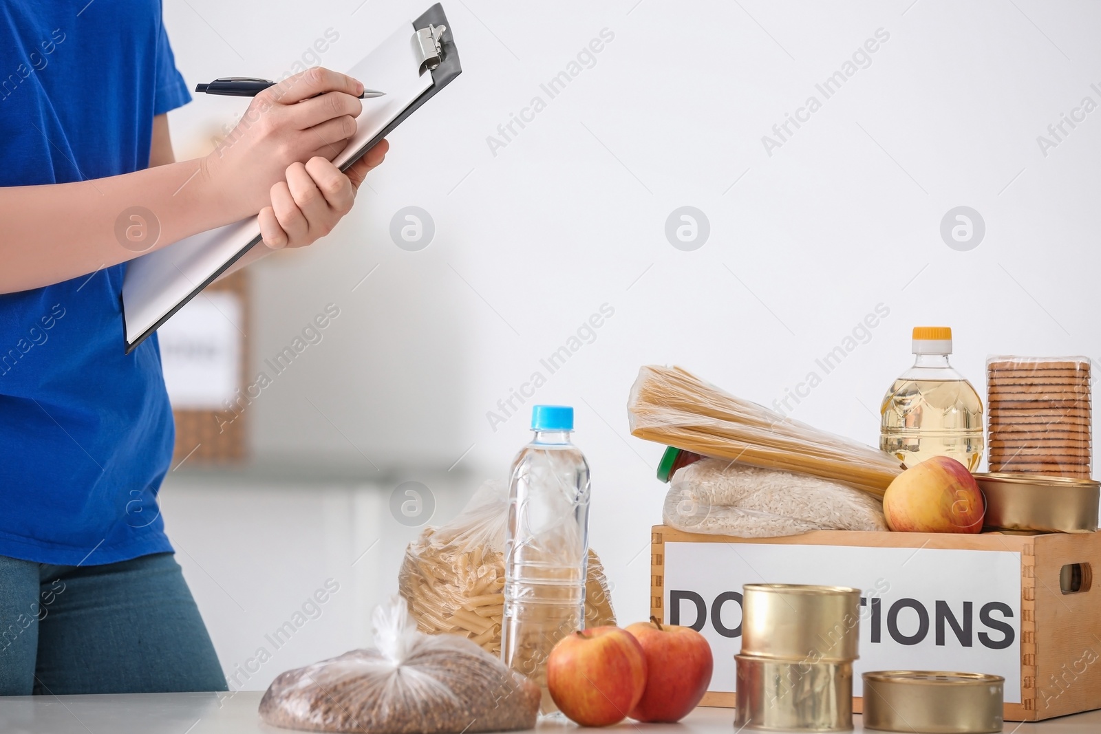 Photo of Female volunteer listing food products from donation box indoors