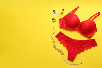 Photo of Flat lay composition with sexy women's underwear on yellow background, space for text